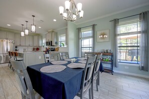 A modern kitchen with white cabinets, stainless steel appliances, and a dining area with a blue tablecloth and chairs. - Waterfront Interlachen Retreat w/ Dock on Lake Ida (Interlachen)