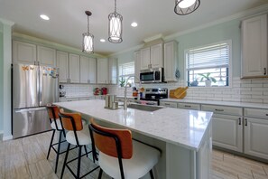 A modern kitchen with white cabinets, a large island with bar stools, stainless steel appliances, and pendant lighting. - Waterfront Interlachen Retreat w/ Dock on Lake Ida (Interlachen)