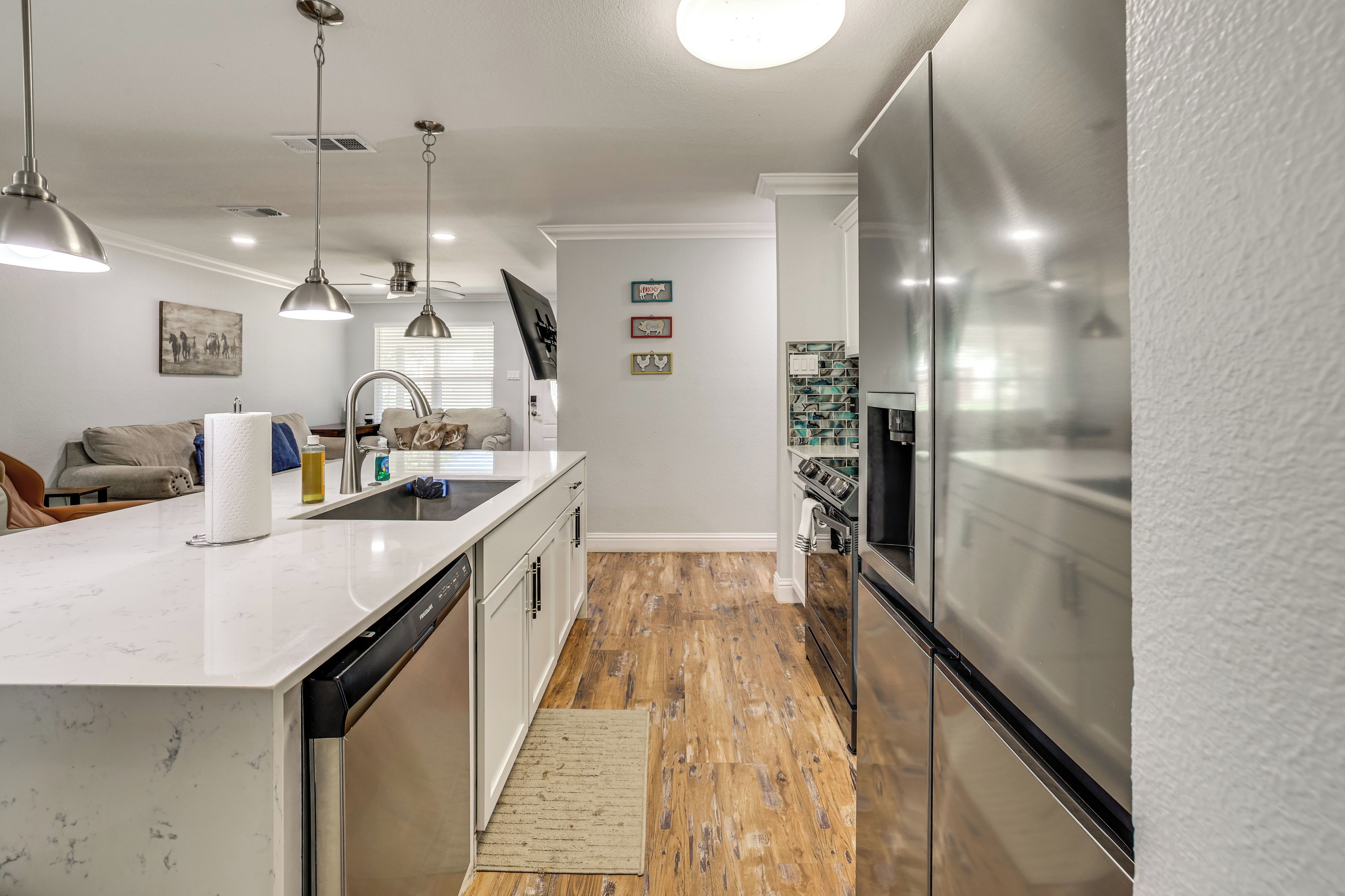 A modern kitchen with stainless steel appliances, a white countertop, and pendant lighting.
