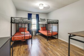 A dormitory room with bunk beds, a wooden floor, a ceiling light, and a window with curtains. - Walk to At&t Stadium! Massage Chair & Cowboy Pool (Arlington)