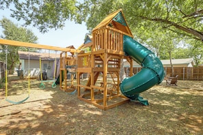 Una estructura de juego de madera con tobogán y columpios.
