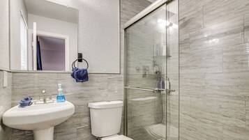 A bathroom with a sink, toilet, and glass shower enclosure.