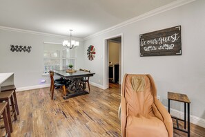 A dining area with a wooden table, chairs, and a chandelier. There is a wall with a decorative sign and a door leading to another room. - Walk to At&t Stadium! Massage Chair & Cowboy Pool (Arlington)