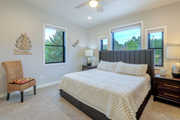 A bedroom with a large bed, a chair, a nightstand, and a ceiling fan. - Pet-friendly, Walkable Spearfish Townhome w/ Yard (Spearfish)