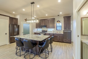 A modern kitchen with a central island, dark wooden cabinets, stainless steel appliances, and a pendant light fixture. - Pet-friendly, Walkable Spearfish Townhome w/ Yard (Spearfish)