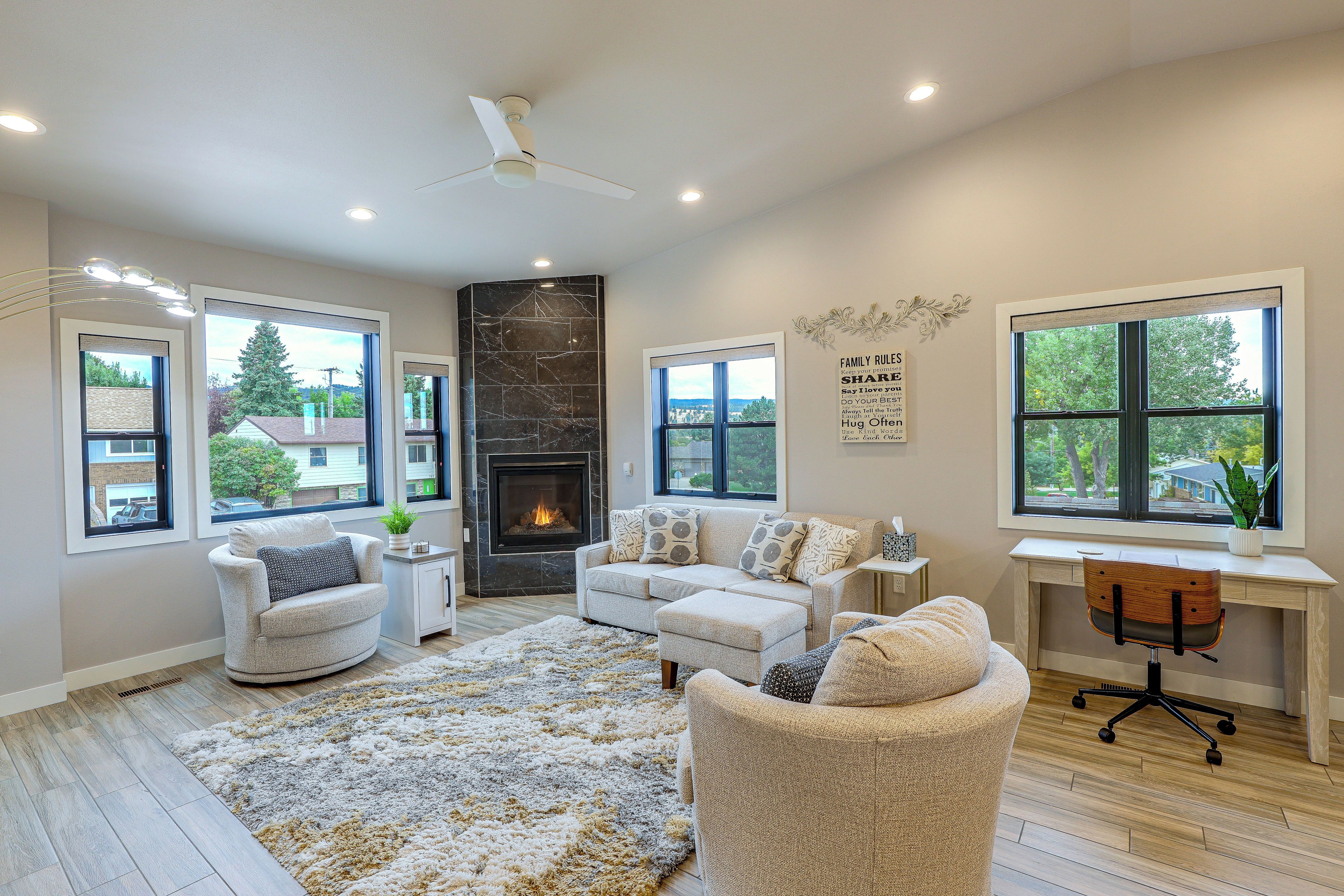 A modern living room with a fireplace, seating area, and a desk with a computer.
