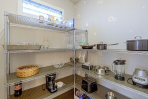 Una cocina con estantes de acero inoxidable que sostienen diferentes utensilios y electrodomésticos.