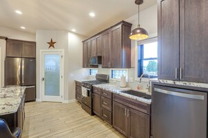 A modern kitchen with dark wood cabinets, stainless steel appliances, and a marble countertop.