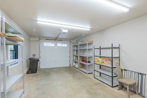 A garage with metal shelving, a rolling bin, and a door with windows. - Pet-friendly, Walkable Spearfish Townhome w/ Yard (Spearfish)