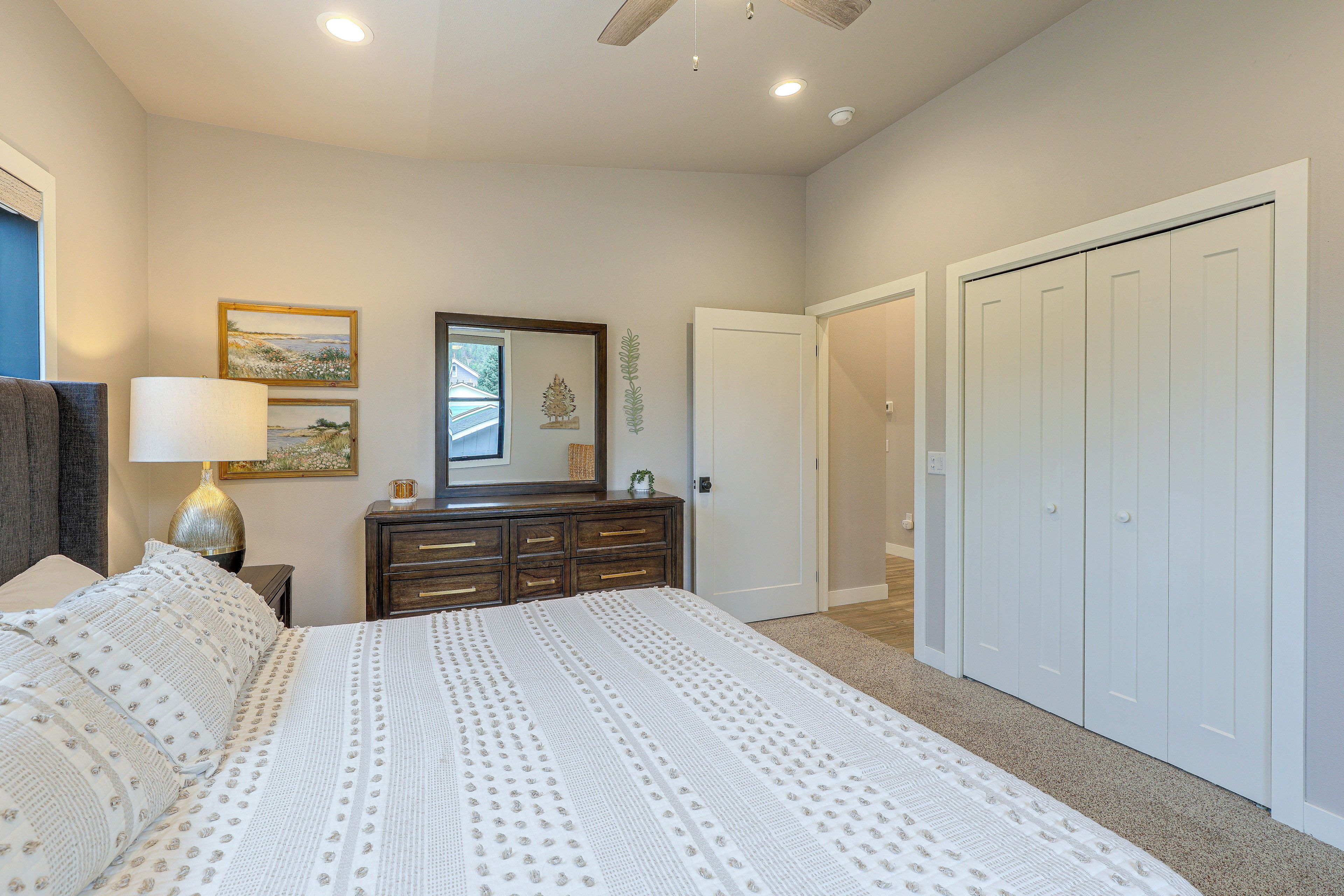 A bedroom with a bed, dresser, and a door leading to another room.