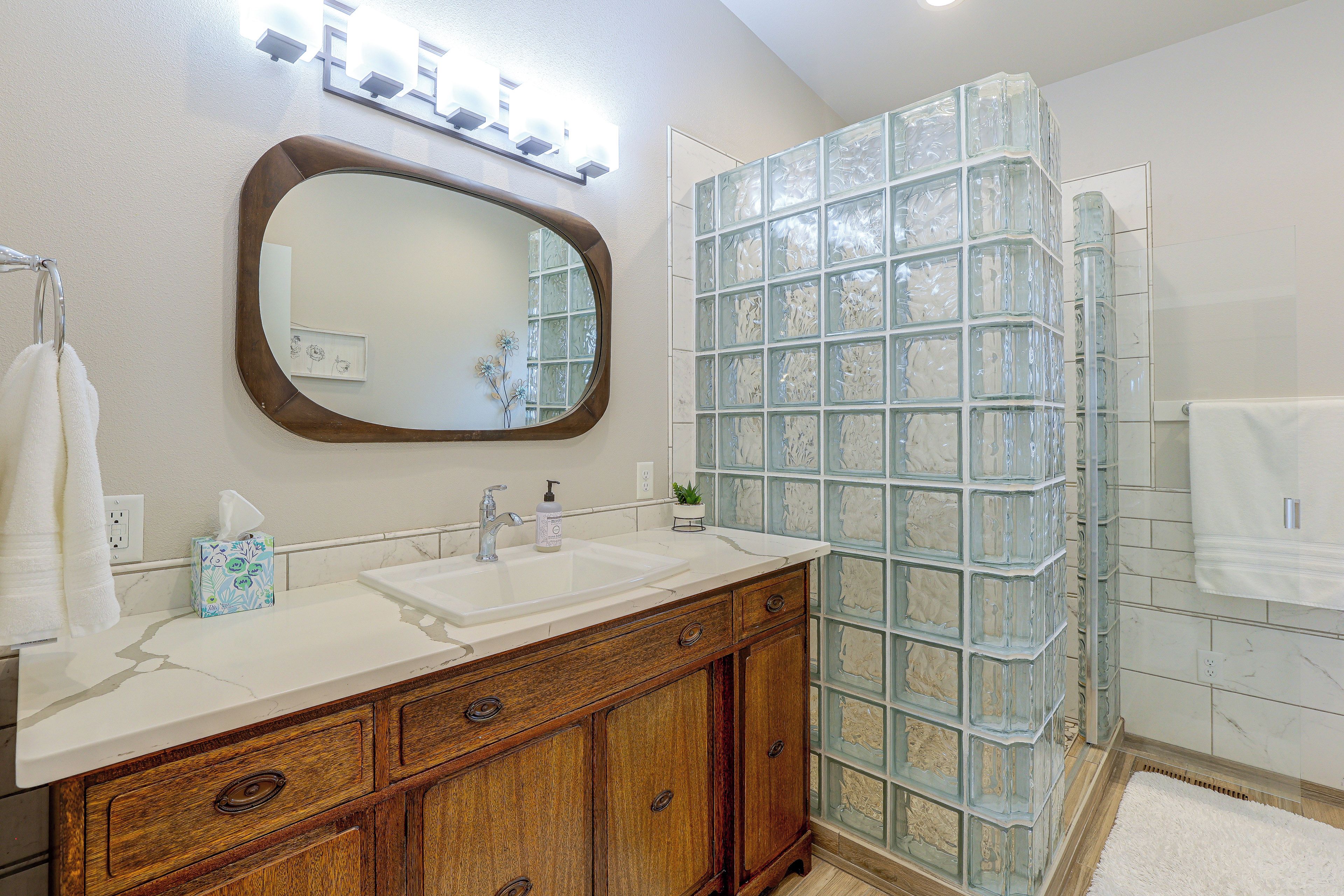 A bathroom with a vanity, a mirror, a glass shower enclosure, and a towel rack.