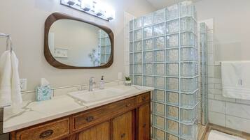 A bathroom with a vanity, a mirror, a glass shower enclosure, and a towel rack.