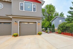 A two-story residential building with a garage, a small attached structure, and a fenced yard with landscaping. - Pet-friendly, Walkable Spearfish Townhome w/ Yard (Spearfish)