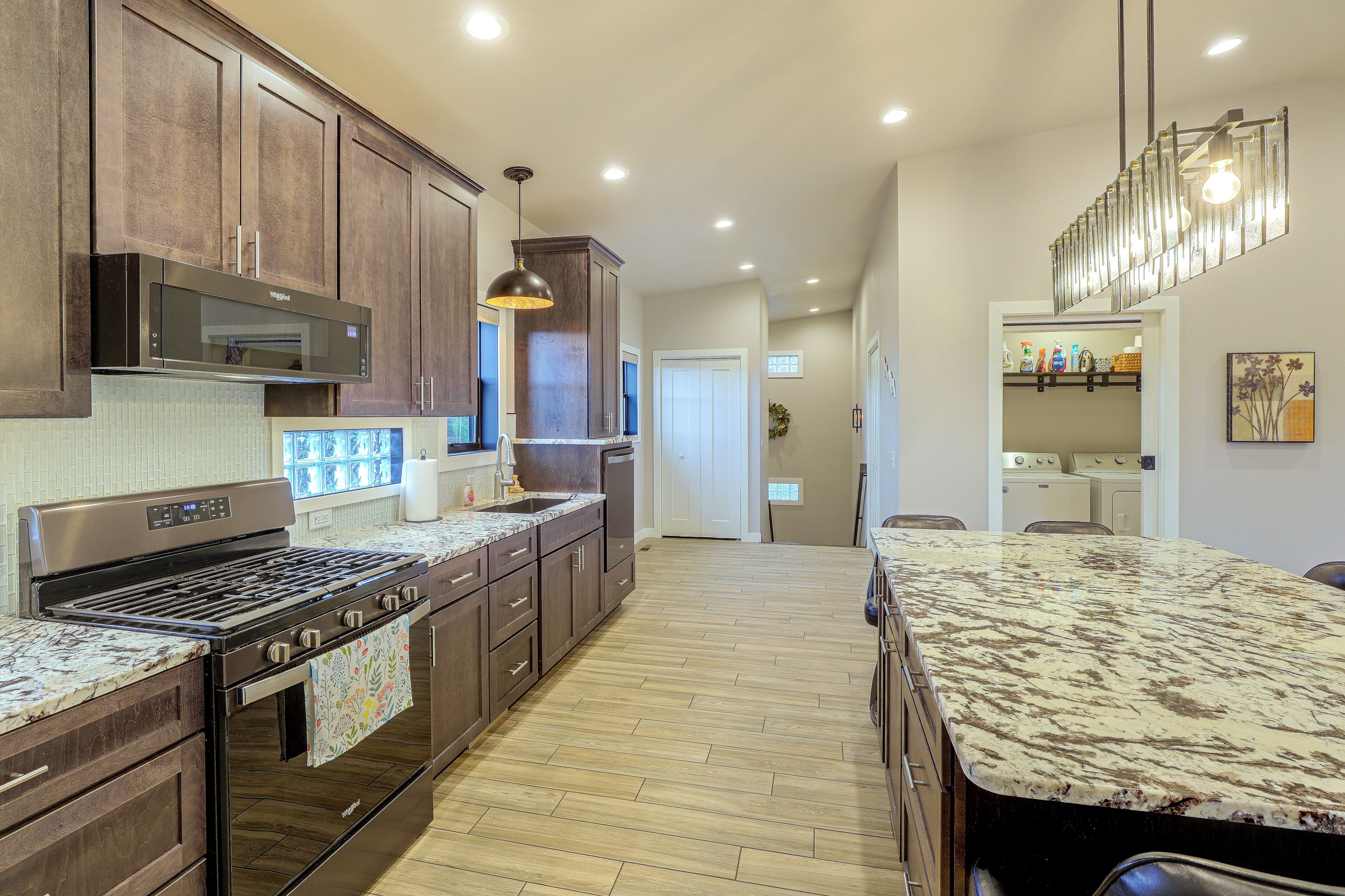 A modern kitchen with dark wood cabinets, stainless steel appliances, and a marble countertop.