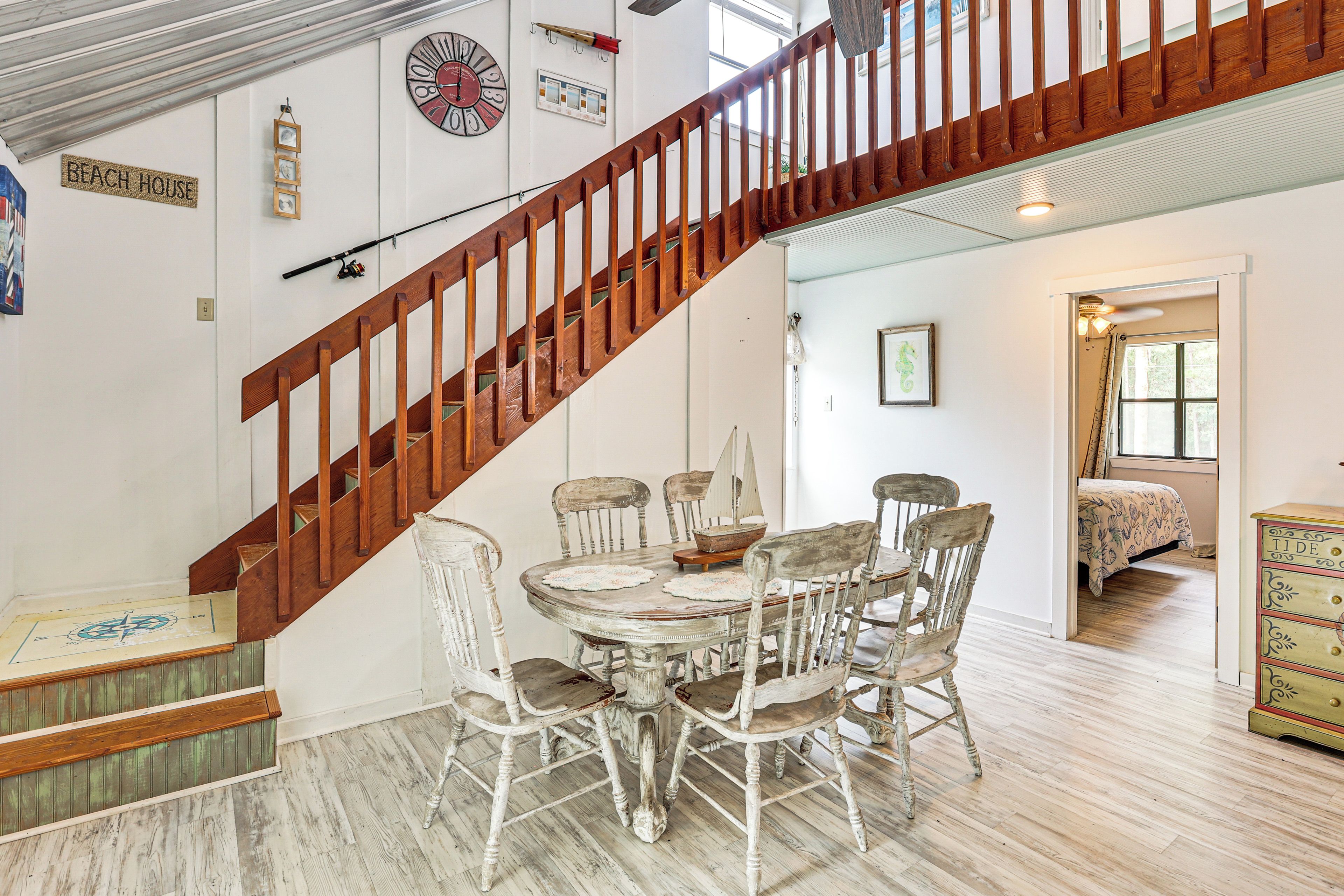 Un escalier avec des rampes en bois mène à un espace repas comprenant une table ronde et plusieurs chaises.