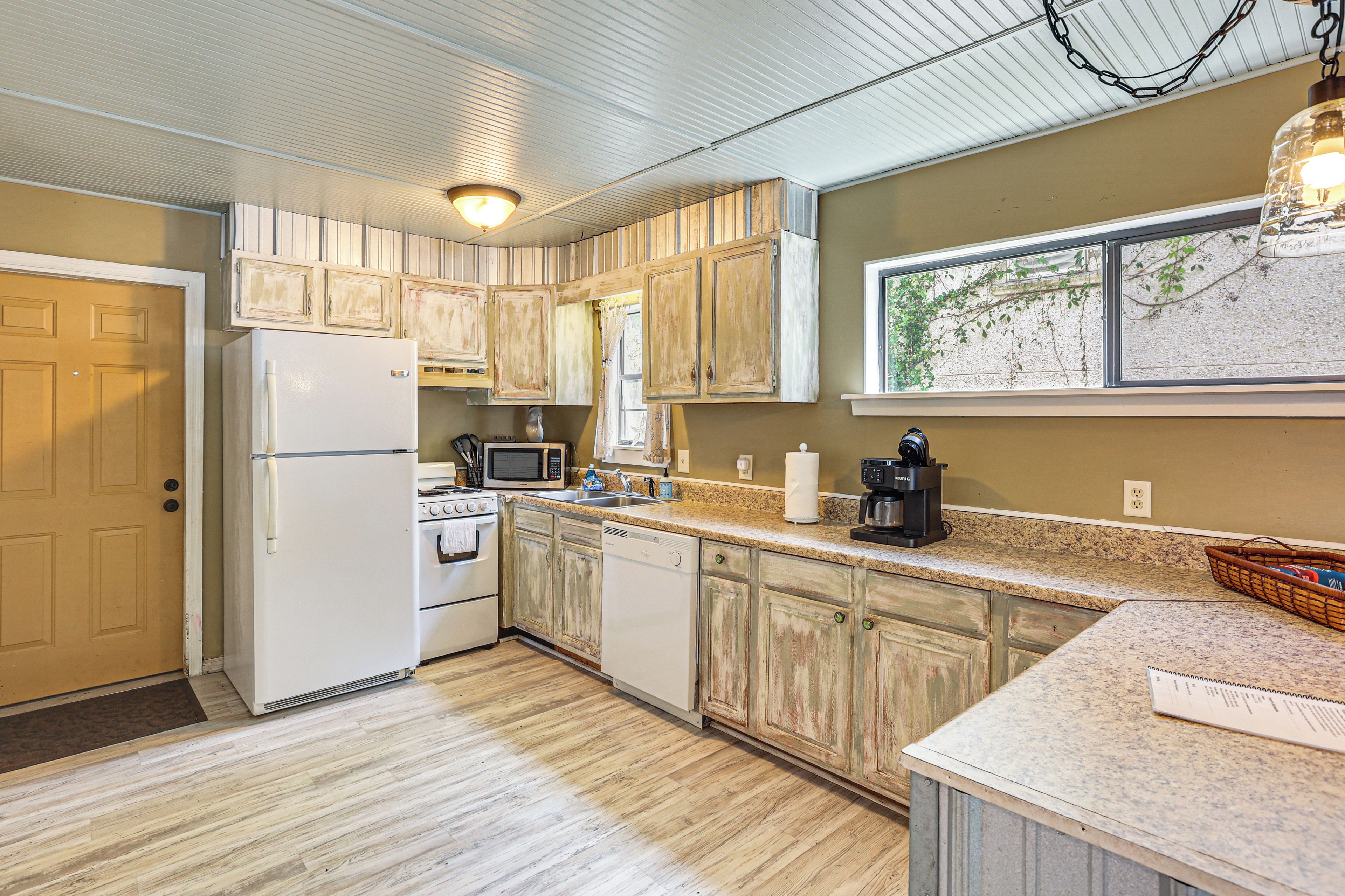 A kitchen with white appliances, wooden cabinets, a granite countertop, and a window with a view.