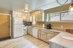 A kitchen with white appliances, wooden cabinets, a granite countertop, and a window with a view. - Fish & Hunt! Waterfront Home w/ Dock in Midway (Midway)