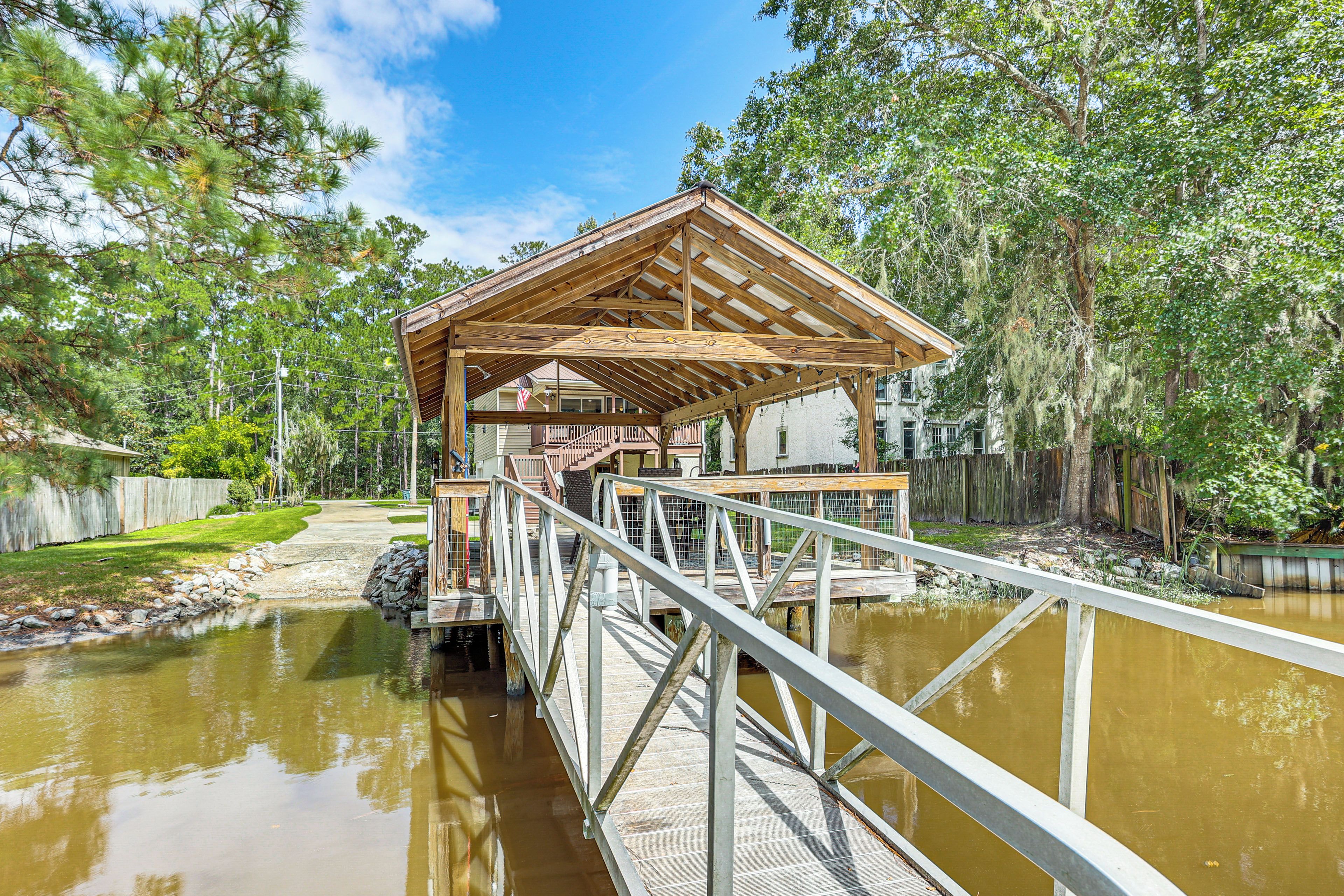 A wooden gazebo with a metal railing over a pond, surrounded by trees.