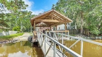 A wooden gazebo with a metal railing over a pond, surrounded by trees.