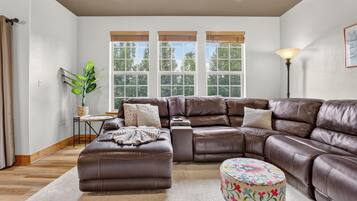 A modern living room with a sectional sofa, a small round ottoman, and a side table with a plant.