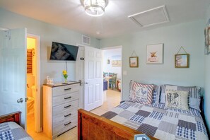 Ein Schlafzimmer mit Bett, Kommode, Fernseher und Kunstwerken an den Wänden.