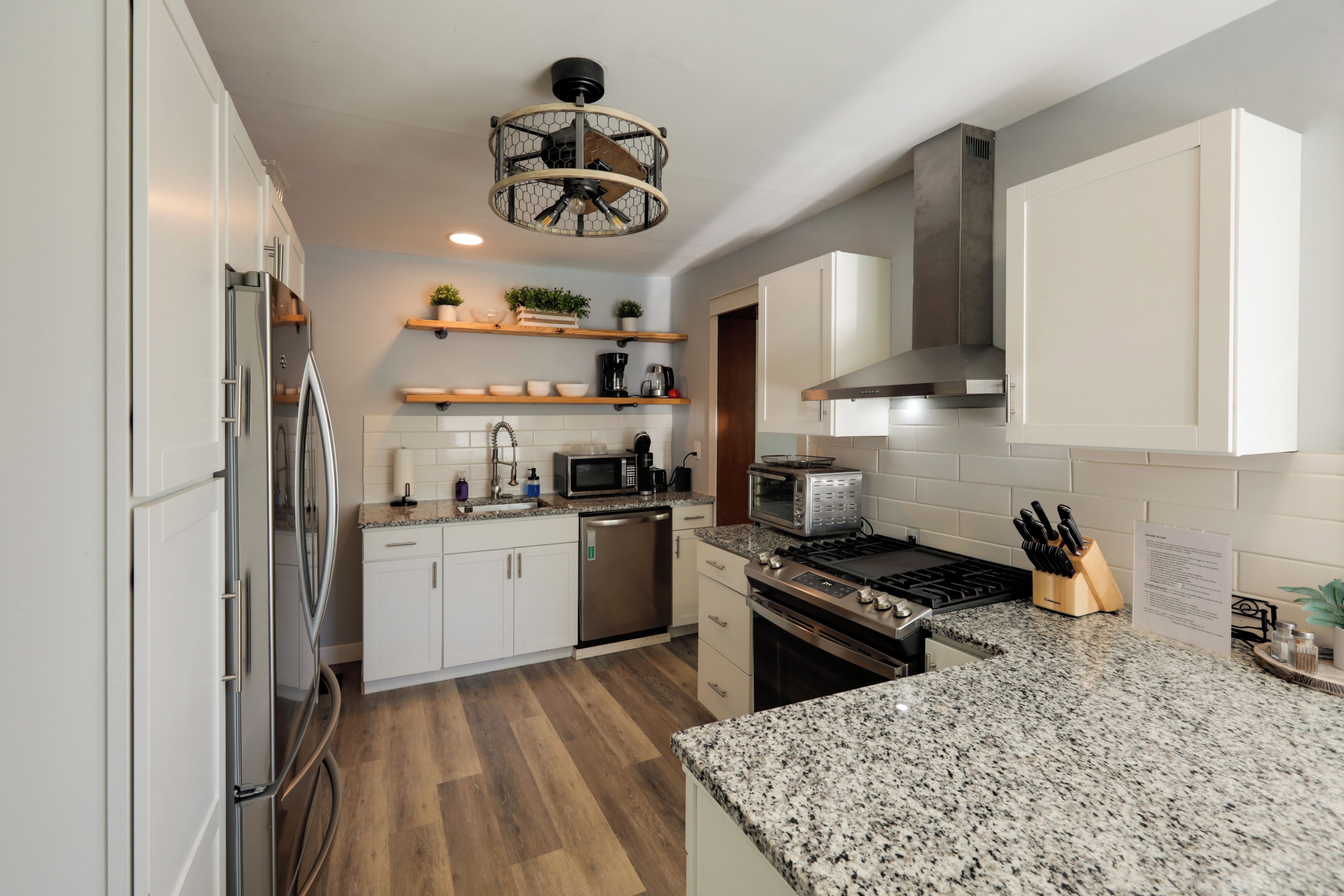 Eine moderne Küche mit Edelstahlgeräten, Holzböden und einer Arbeitsplatte aus Granit.