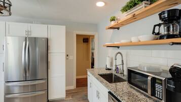 A modern kitchen with a stainless steel refrigerator, a microwave, and a coffee maker on the countertop.