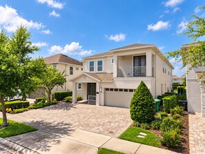 A modern two-story residential building with a garage, a covered driveway, and well-maintained landscaping. - Amazing 9 bedrooms and private pool with spa (Kissimmee)