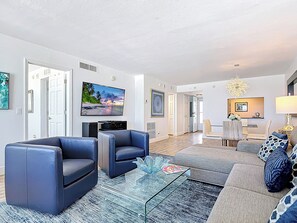 Una sala de estar moderna con un televisor de pantalla plana, sofás de cuero y una mesa de centro de vidrio.
