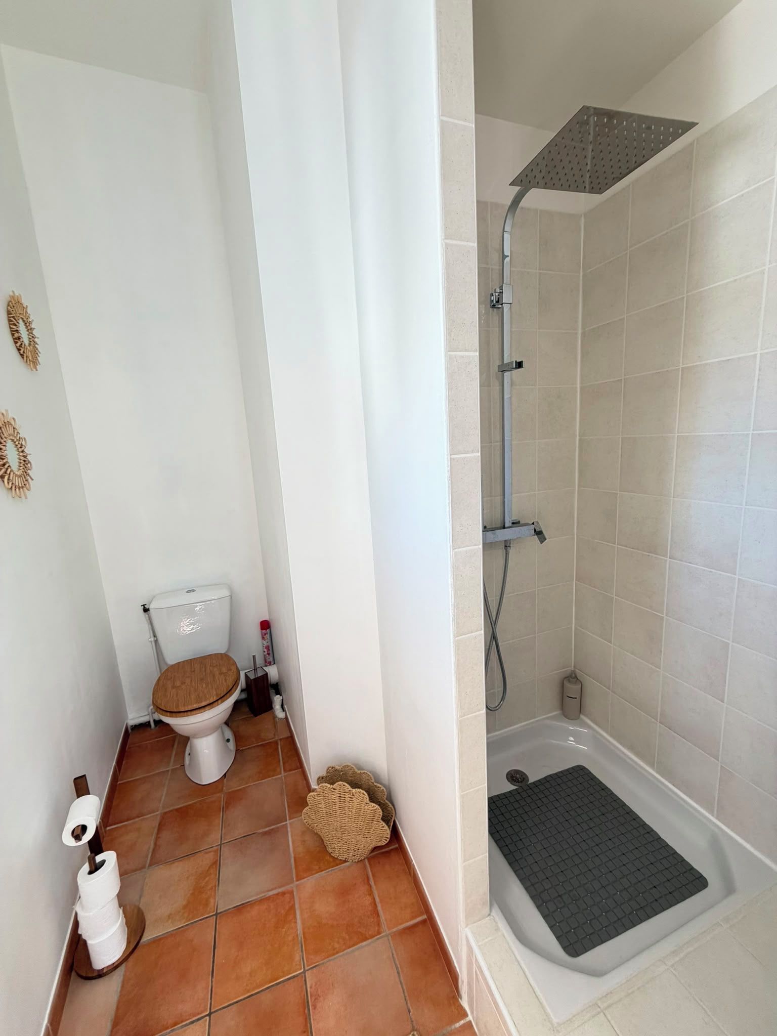 A bathroom with a toilet, a shower, and a tiled floor.