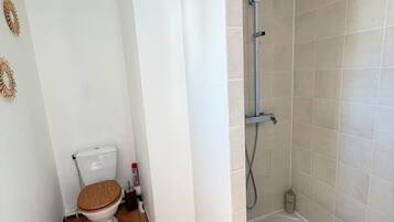 A bathroom with a toilet, a shower, and a tiled floor.
