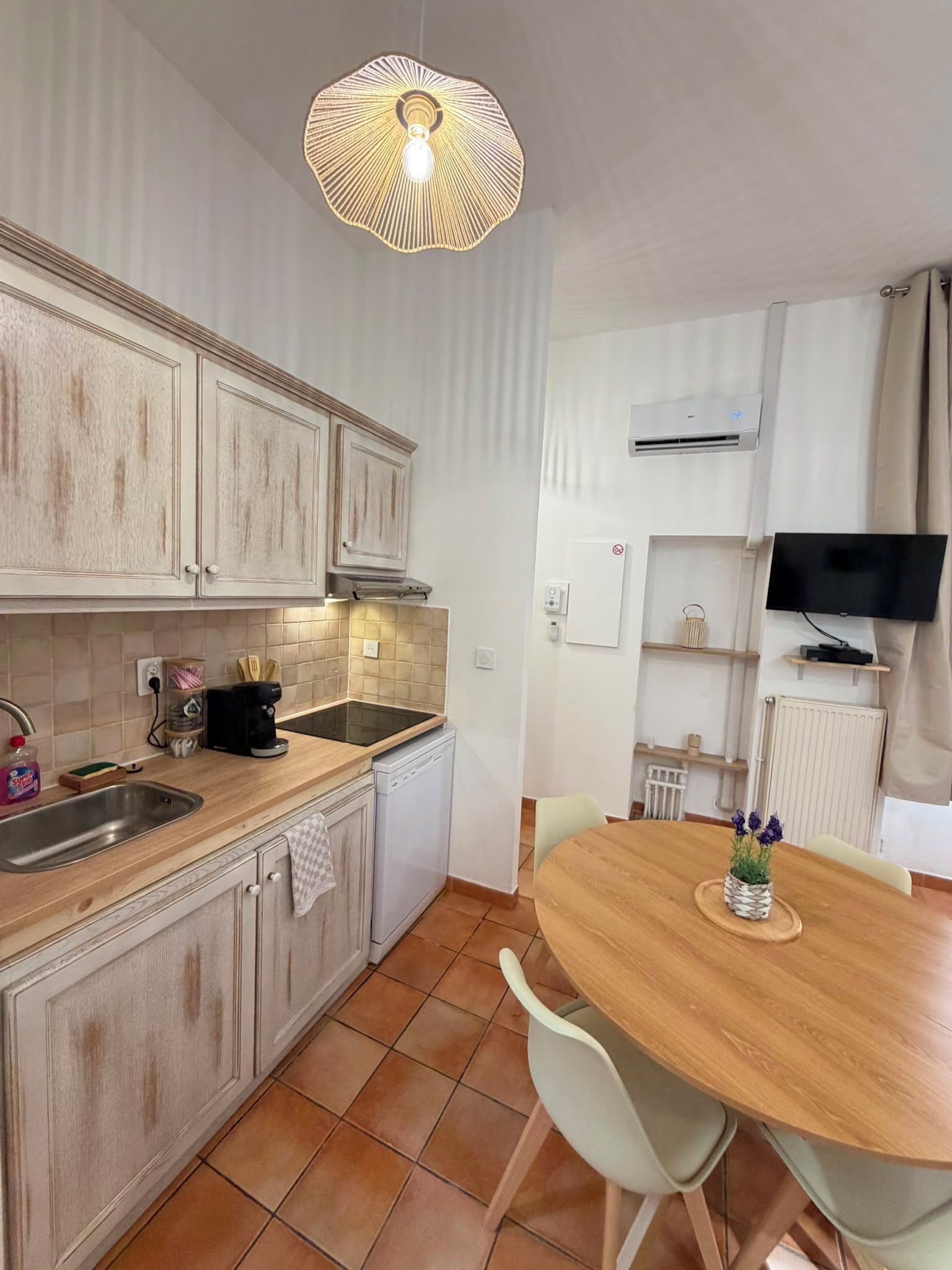 Une cuisine avec un coin repas, un téléviseur et un luminaire au plafond.