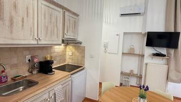 Une cuisine avec un coin repas, un téléviseur et un luminaire au plafond.