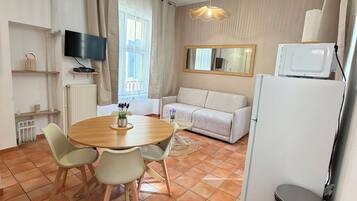 Ett kompakt bostadsutrymme med en matplats, ett litet kök och en sittgrupp.
