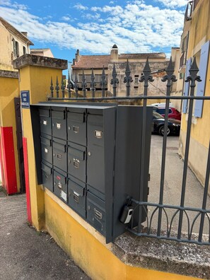 Une barrière de sécurité en métal, adossée à un mur jaune, sur laquelle est apposée une pancarte indiquant : « COUR DES MIRACLES ».