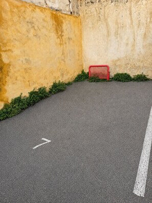 A paved area with a red object, possibly a trash bin, and a white line marking.