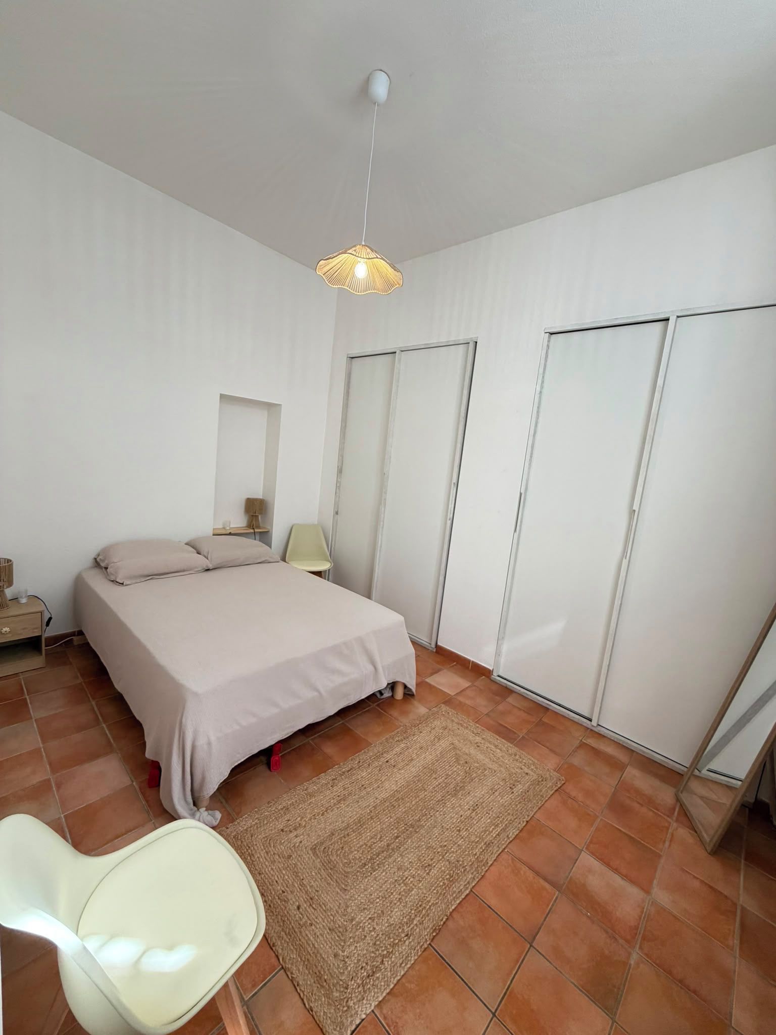 Una camera da letto con un letto, una sedia, un tappeto e una lampada a sospensione.