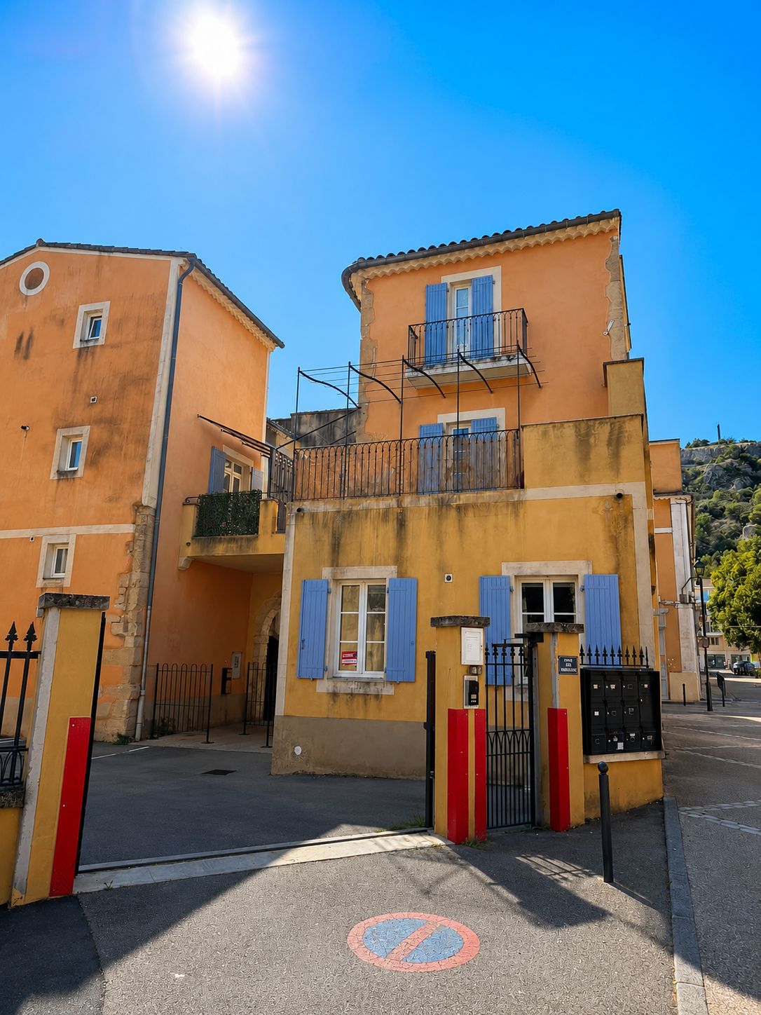 Un immeuble de deux étages doté d’un balcon, d’une grille et d’un panneau indiquant qu’il est interdit de se garer sur le trottoir.