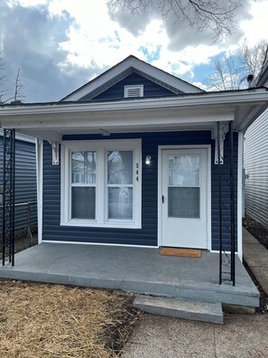 A residential house with a dark blue exterior, a white front door, and a small porch. - Centrally Located Home in Louisville (Louisville)