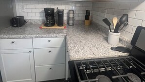 Eine Küche mit weißen Schränken, einem Gasherd, einer Kaffeemaschine und einem Toaster.