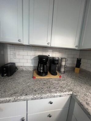 A kitchen with white cabinets, a toaster, a coffee maker, and a kettle on a granite countertop. - Centrally Located Home in Louisville (Louisville)