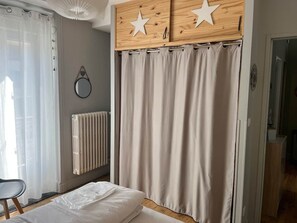 Ein Schlafzimmer mit einem Bett, einem Holfisch mit Sternenmotiven, einem Heizkörper und einem Vorhang.