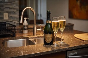 A kitchen counter with a bottle of champagne and two glasses of champagne. - Whimsical Wonders Sweetwater Club Near Disney (Kissimmee)