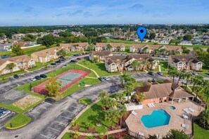 A residential area with a swimming pool, tennis court, and multiple housing units. - Whimsical Wonders Sweetwater Club Near Disney (Kissimmee)