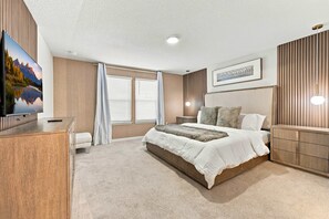 A bedroom with a bed, bedside tables, a TV, and a painting. - Family Dream Home Pool Arcade Slide Bed 2472 (Kissimmee)