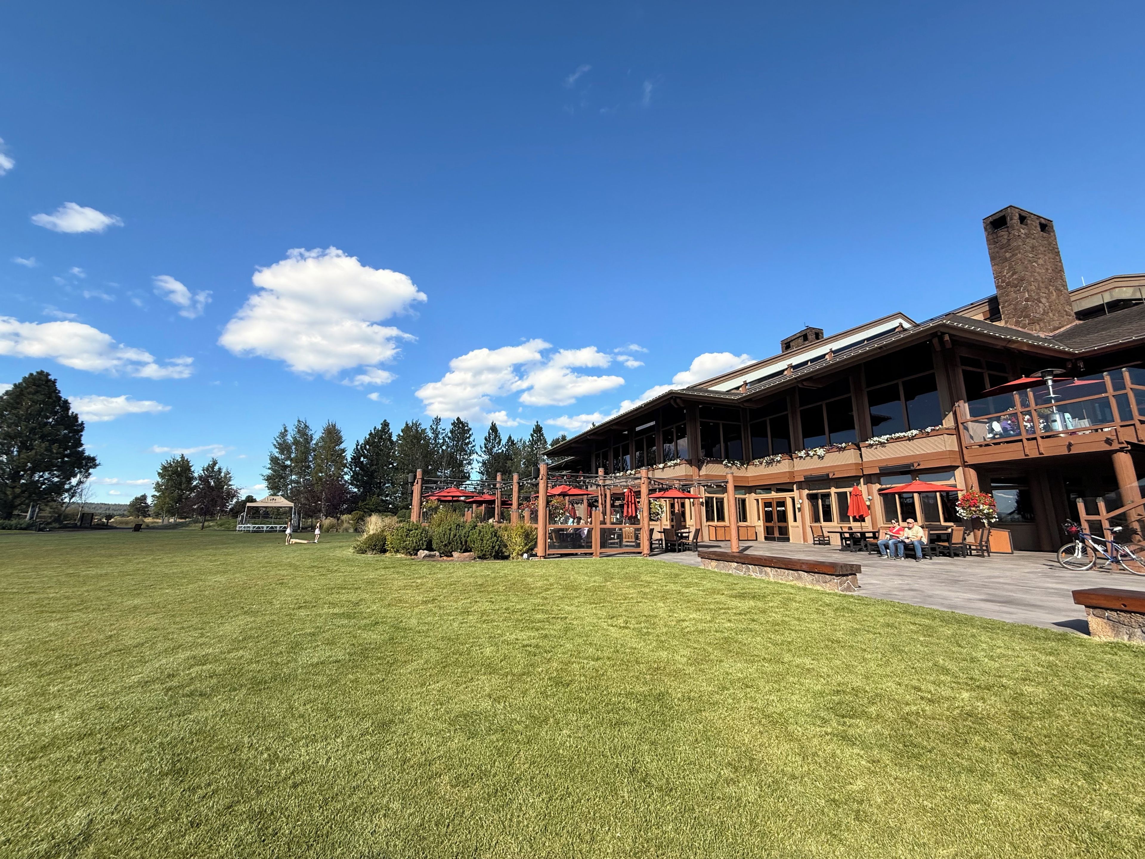 A building with a large lawn in front, wooden exterior, and a chimney.