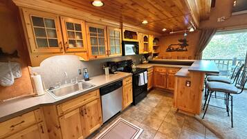 A wooden cabin kitchen with a sink, stove, and dining area.