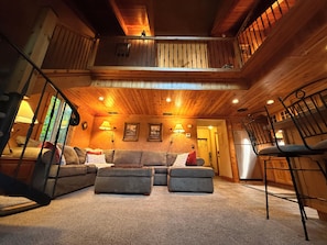 Ein gemütliches Blockhaus-Interieur mit Holzbalkendecke, einer Sofagarnitur und einem Essbereich.