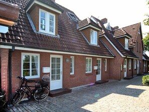 Eine Reihe von Ziegelhäusern mit Satteldächern und Fensterrahmen in Weiß.