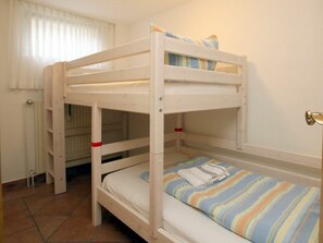 Ein Schlafraum mit Etagenbett, Fenster, Heizkörper und Tür.